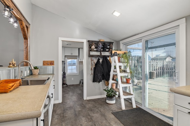 kitchen with vaulted ceiling, dark wood-type flooring, sink, dishwasher, and white cabinetry