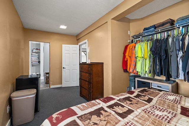 bedroom with a closet, dark carpet, and a textured ceiling