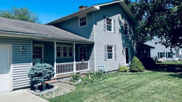 920 Woodbine St, Willard, OH 44890 - view of side of home with covered porch, a yard, a chimney, and a garage