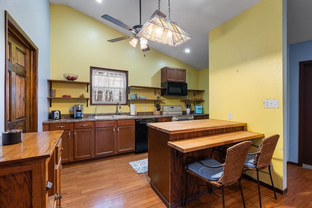 kitchen with butcher block counters, sink, a breakfast bar area, pendant lighting, and black appliances