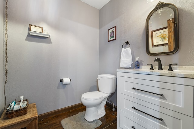 bathroom with vanity, toilet, and hardwood / wood-style floors