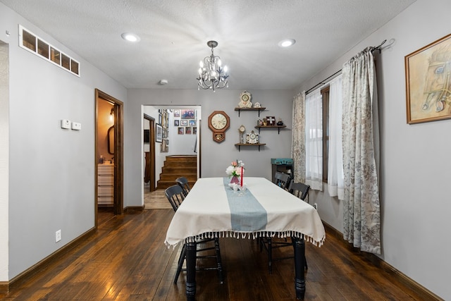 dining area featuring a textured ceiling, dark wood-type flooring, and a chandelier