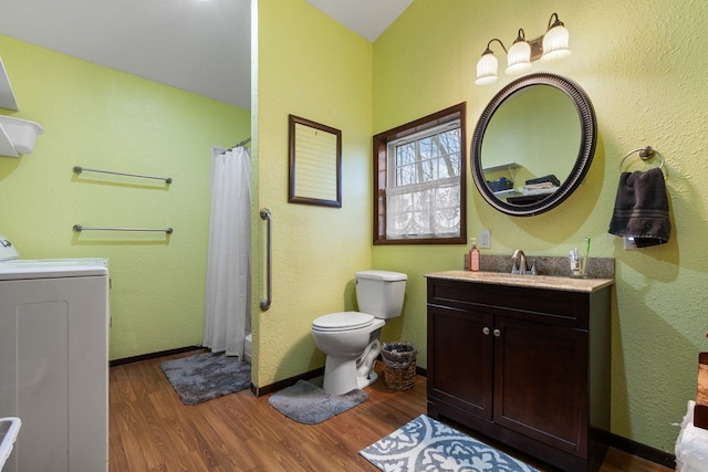 bathroom with washer / clothes dryer, hardwood / wood-style flooring, vanity, walk in shower, and toilet