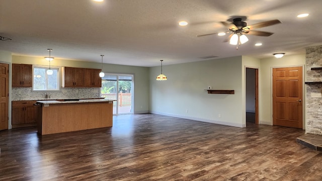 kitchen featuring tasteful backsplash, ceiling fan, dark hardwood / wood-style floors, a kitchen island, and hanging light fixtures