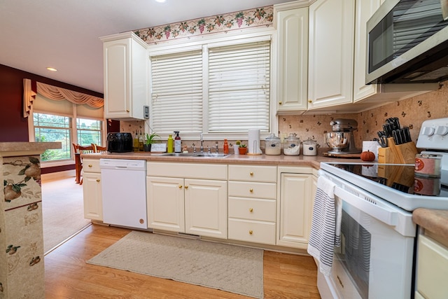 kitchen featuring white cabinetry, sink, tasteful backsplash, white appliances, and light wood-type flooring