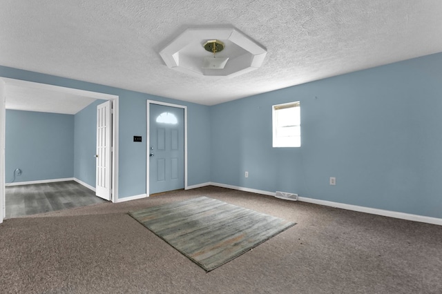 entrance foyer with dark carpet and a textured ceiling