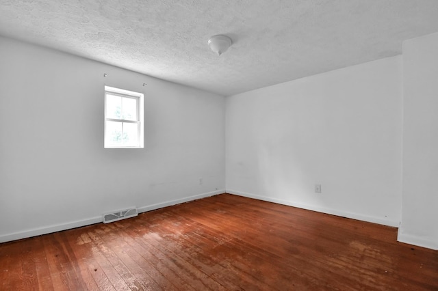 spare room with a textured ceiling and hardwood / wood-style flooring