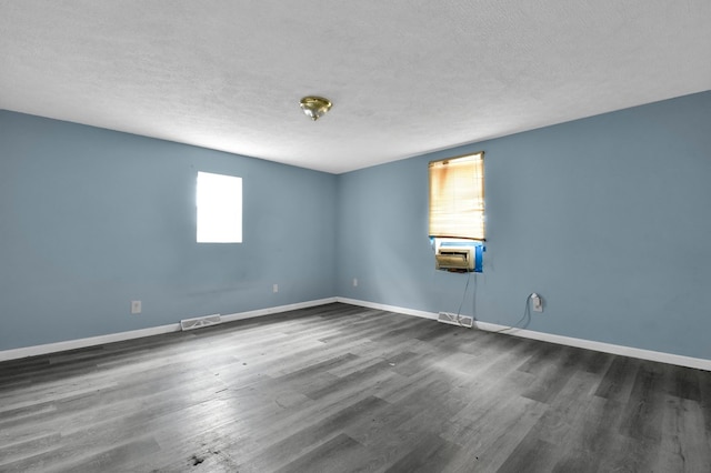 spare room with a wealth of natural light, dark hardwood / wood-style flooring, and a textured ceiling