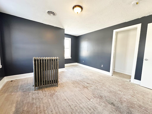 unfurnished room with hardwood / wood-style flooring, radiator heating unit, and a textured ceiling