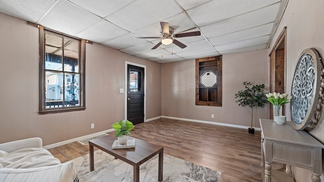 living room featuring a drop ceiling, hardwood / wood-style flooring, and ceiling fan