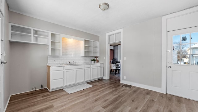 kitchen featuring tasteful backsplash, white cabinetry, sink, light hardwood / wood-style floors, and a textured ceiling