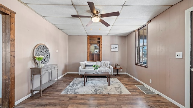 living area featuring ceiling fan, a paneled ceiling, and dark hardwood / wood-style flooring