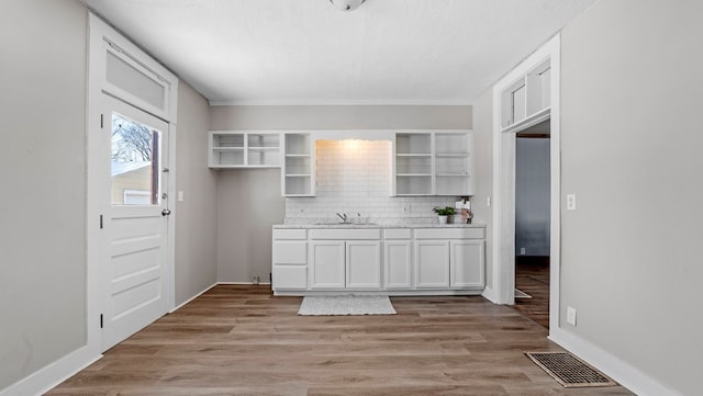 kitchen with sink, light hardwood / wood-style floors, decorative backsplash, and white cabinets