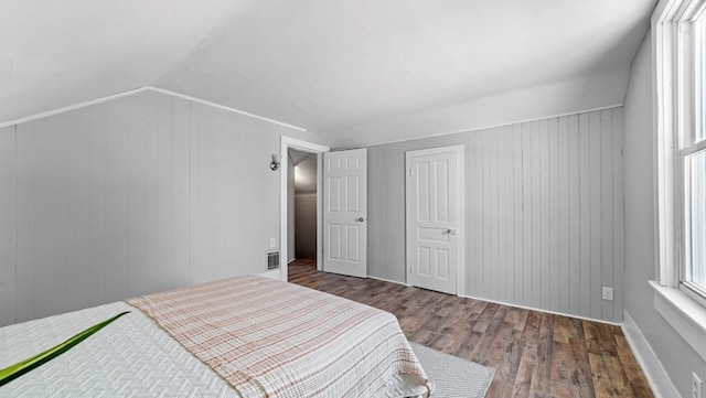 bedroom featuring dark hardwood / wood-style flooring, vaulted ceiling, and wooden walls