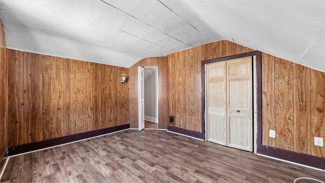 bonus room with vaulted ceiling, dark wood-type flooring, and wood walls