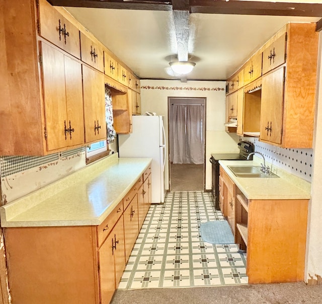 kitchen featuring under cabinet range hood, a sink, electric range oven, freestanding refrigerator, and light countertops