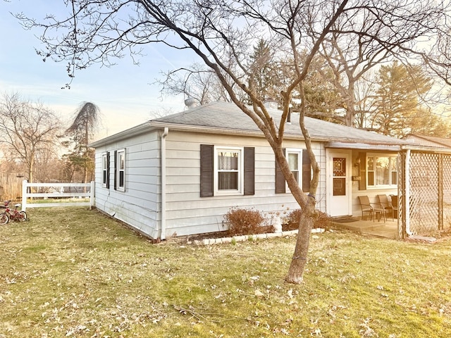 view of front of home featuring a patio area, roof with shingles, a front lawn, and fence