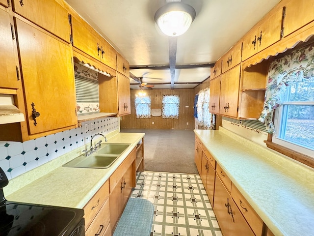 kitchen with electric range, a sink, wood walls, light countertops, and light floors