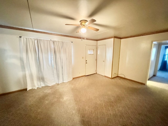 carpeted spare room with ceiling fan, baseboards, and ornamental molding