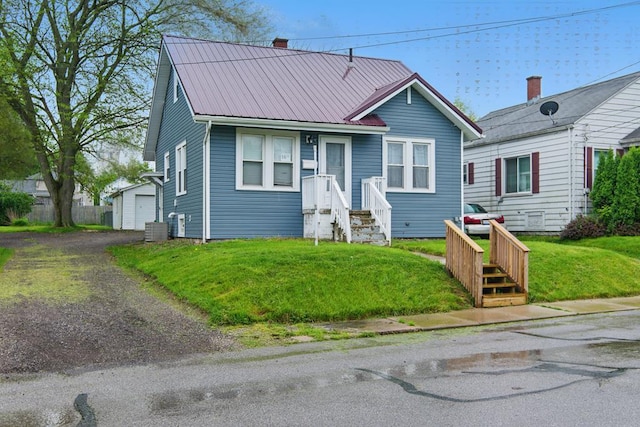 16.5 Monroe Ave, Shelby, OH 44875 - view of front of home with metal roof, a front lawn, central AC, a detached garage, and an outdoor structure