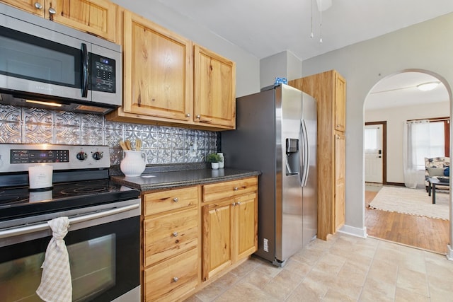 16.5 Monroe Ave, Shelby, OH 44875 - kitchen featuring appliances with stainless steel finishes, arched walkways, decorative backsplash, dark countertops, and ceiling fan