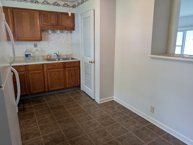272 Hillside St, Mount Gilead, OH 43338 - kitchen featuring a sink, freestanding refrigerator, brown cabinets, light countertops, and baseboards