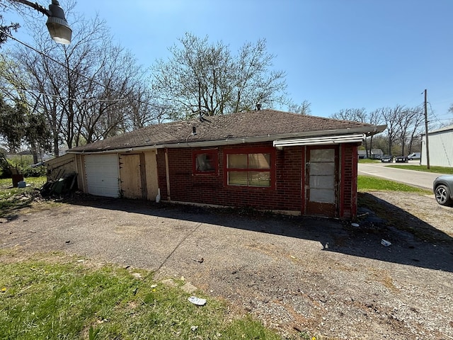 1015 N Cole St, Lima, OH 44805 - exterior space featuring an attached garage, a shingled roof, aphalt driveway, and brick siding