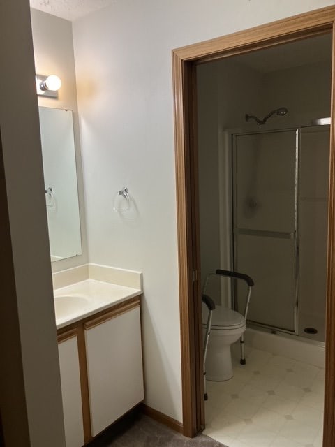 bathroom with a shower with door, vanity, and toilet