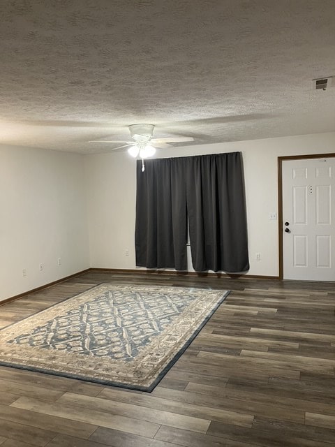 unfurnished room featuring a textured ceiling, ceiling fan, and dark wood-type flooring