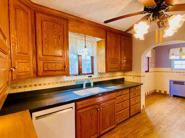 kitchen with sink, hanging light fixtures, radiator heating unit, white dishwasher, and a textured ceiling