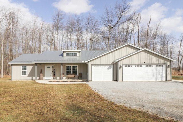 view of front of home with a porch, gravel driveway, an attached garage, a front yard, and metal roof