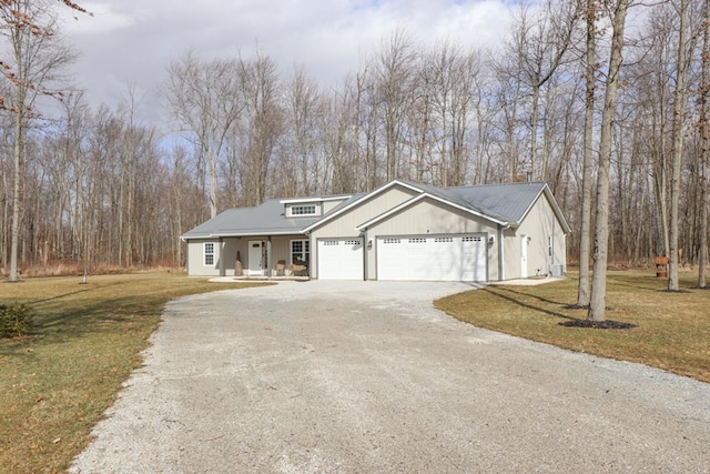 view of front of house featuring a garage, a porch, gravel driveway, and a front yard