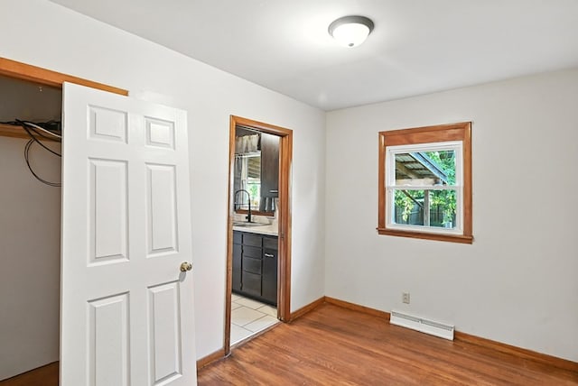 438 Mackey St, Galion, OH 44833 - unfurnished bedroom featuring light wood finished floors, baseboard heating, and ensuite bathroom