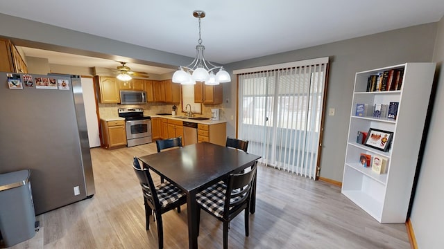 dining area featuring ceiling fan with notable chandelier, sink, and light hardwood / wood-style floors