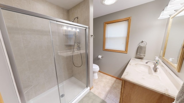 bathroom featuring tile patterned floors, vanity, toilet, and a shower with shower door