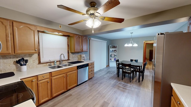 kitchen featuring sink, light hardwood / wood-style flooring, stainless steel appliances, decorative backsplash, and decorative light fixtures