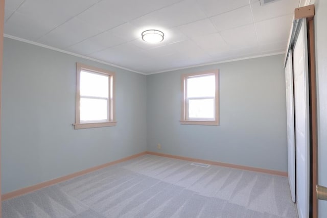 empty room with light colored carpet, baseboards, a healthy amount of sunlight, and ornamental molding