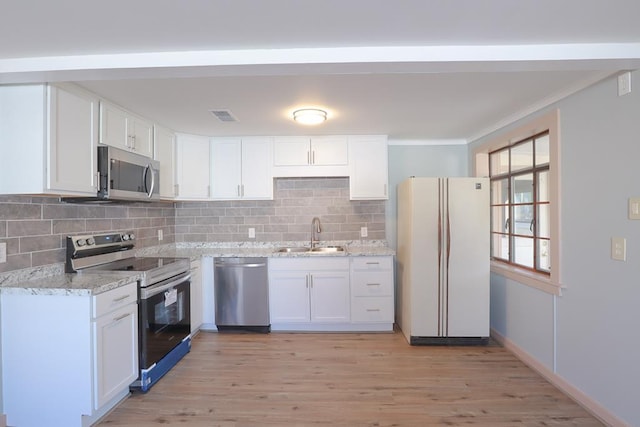 kitchen featuring visible vents, a sink, ornamental molding, stainless steel appliances, and white cabinetry