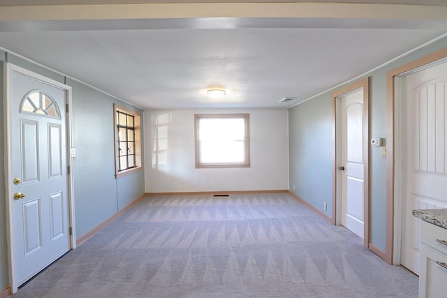 unfurnished room with visible vents, light colored carpet, and baseboards