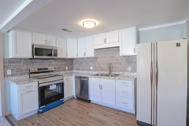 kitchen with visible vents, a sink, white cabinetry, appliances with stainless steel finishes, and light stone countertops