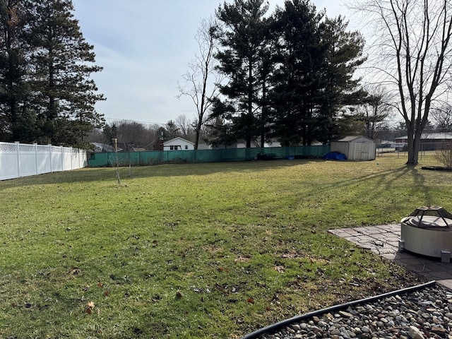 view of yard with a shed, a fenced backyard, and an outdoor structure