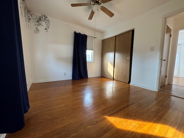 unfurnished bedroom featuring a ceiling fan, a closet, baseboards, and wood finished floors