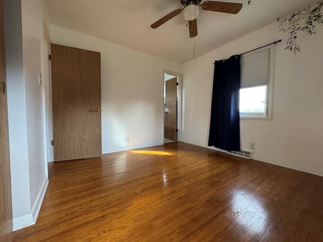 empty room featuring ceiling fan, wood finished floors, visible vents, and baseboards