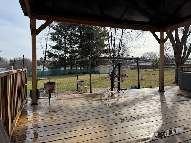 wooden deck featuring a yard, a gazebo, a shed, a fenced backyard, and an outdoor structure