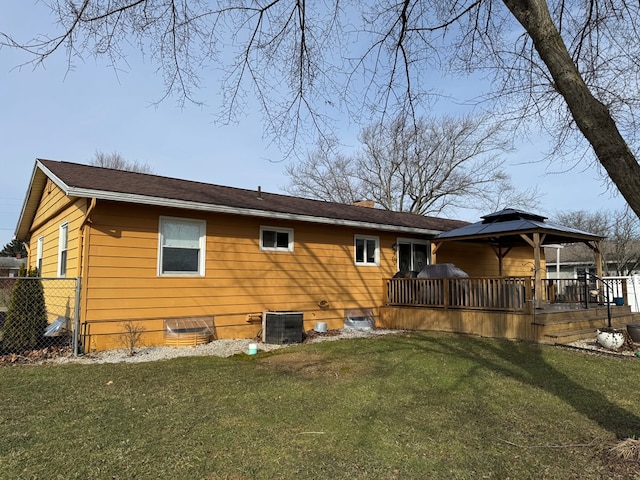 rear view of house with a yard, a chimney, a gazebo, central AC unit, and fence