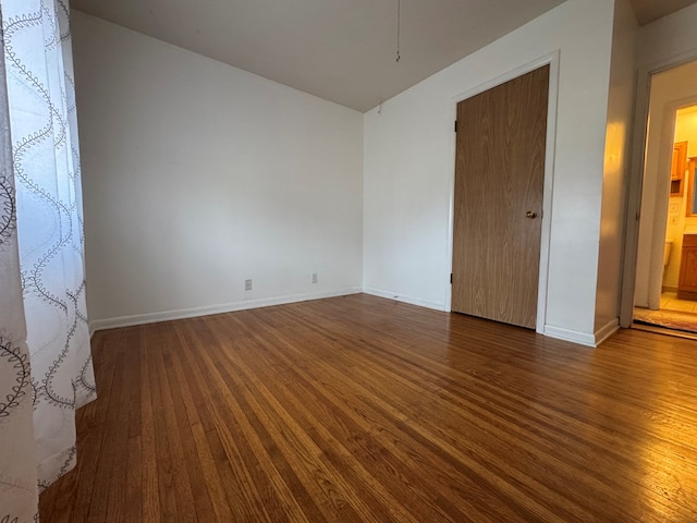 empty room featuring dark wood-style floors and baseboards