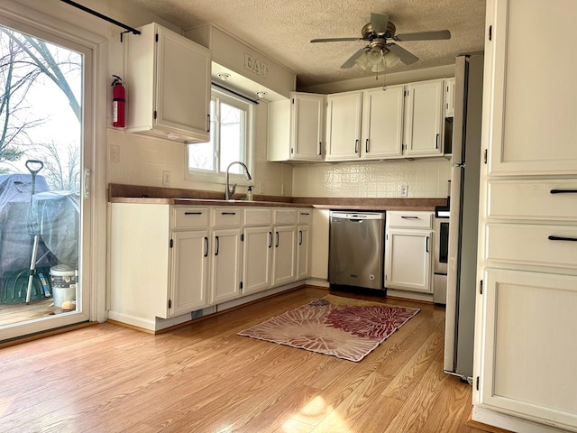 kitchen featuring dishwasher, dark countertops, white cabinetry, and light wood-style floors