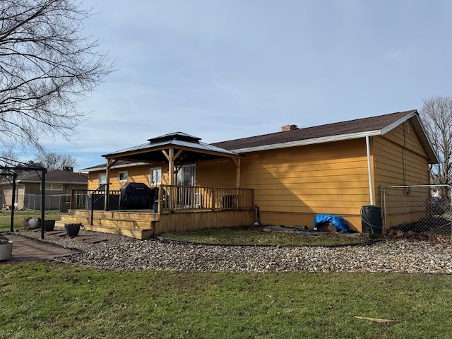 rear view of property featuring a porch, fence, a chimney, and a lawn