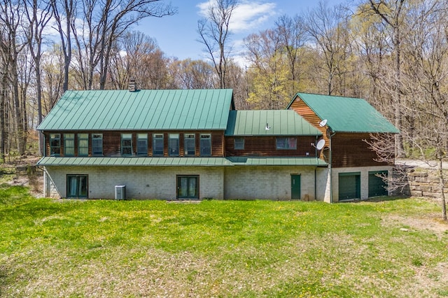 rear view of house featuring a standing seam roof, a yard, central air condition unit, and metal roof