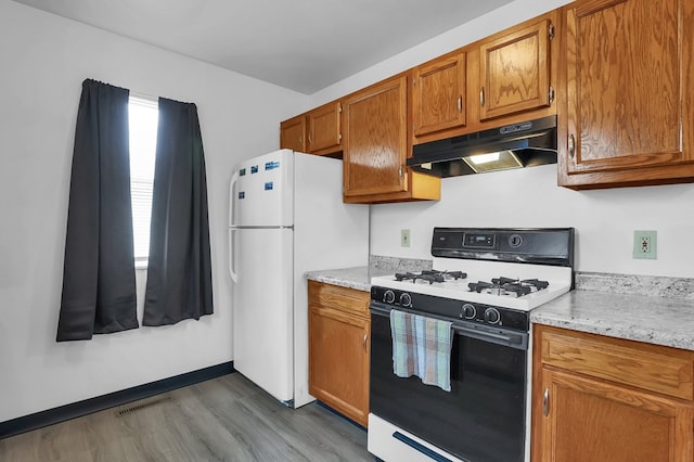 528 N Mulberry St, Street, OH 44902 - kitchen featuring range with gas cooktop, under cabinet range hood, brown cabinets, dark wood-type flooring, and freestanding refrigerator
